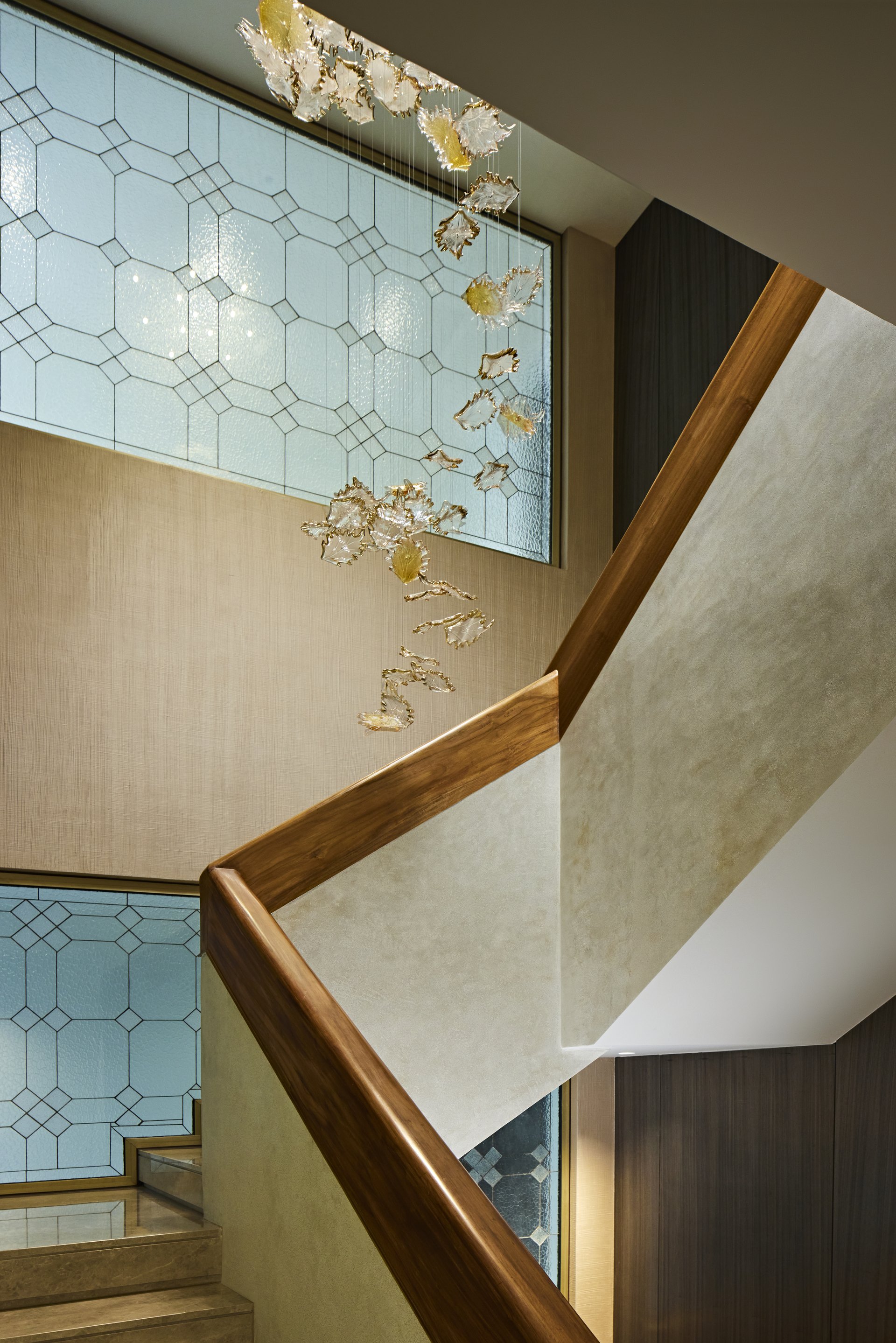 Interior stair with a timber handrail, patterned glazing and sculptural lighting